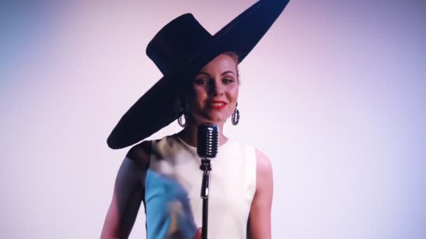 A woman in big retro hat singing on the stage. White background changes to red — Stock Video