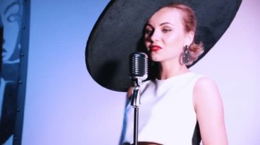 Beyaz bir arka plan üzerinde bir performans sahne alanı'ndaki sahip büyük retro şapkalı bir kadın.