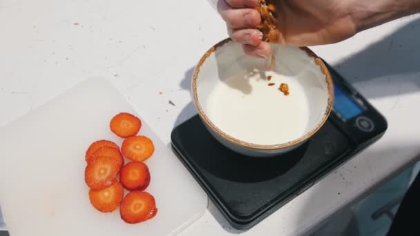 Yogurt bianco nella ciotola. Granola spruzzante sullo yogurt — Video Stock