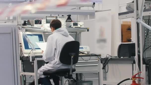 Elektronica ingenieurs die werkzaam zijn in het lab. Ingenieurs zitten aan de tafel en werken op de computer. Overzicht van Office — Stockvideo