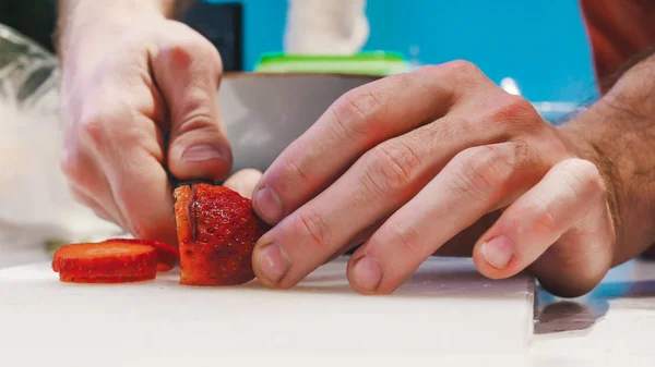 Человек режет клубнику на ломтиках для украшения — стоковое фото