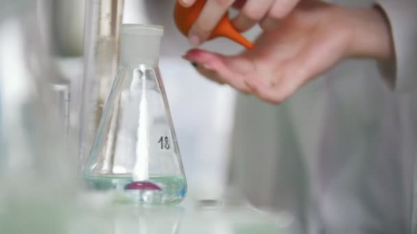 Laboratorium chemiczne. Młody laborant ma kolby z cieczy w jej ręce — Wideo stockowe