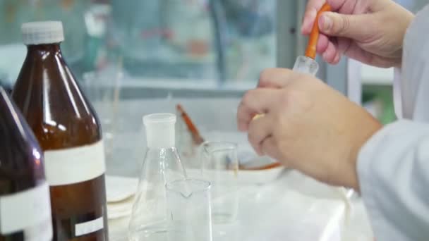 Eine Frau gießt lila Flüssigkeit in einen Kolben — Stockvideo