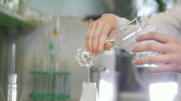 Een vrouw giet water in een maatkolf van glas — Stockvideo