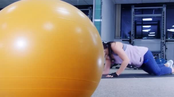 Opleiding. Een jonge vrouw pompen haar spieren van de hand leunend op de vloer — Stockvideo