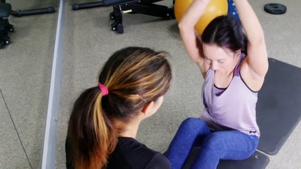 トレーニング 若い女性は トレーナーにダンベルを持って腹筋をポンプします ミディアム ショット — ストック動画