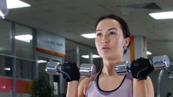 Entraînement. Une jeune femme pompe ses muscles de la main avec un haltère. Je me regarde dans le miroir. Portrait — Video