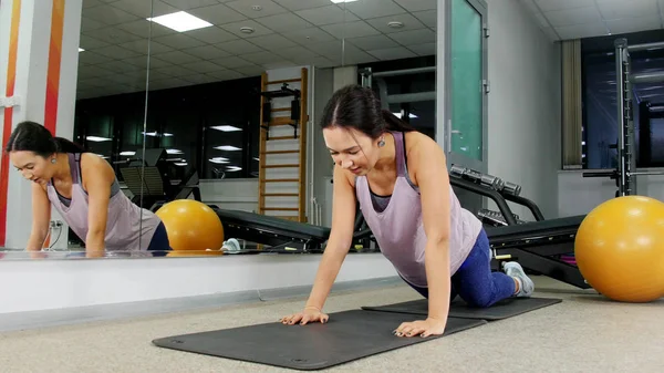 Opleiding. Een jonge vrouw in de sportschool doet push ups vanaf de vloer — Stockfoto