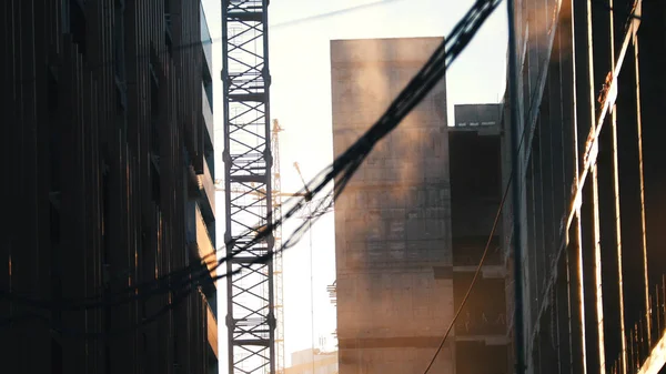 Um estaleiro. Guindaste da torre de trabalho. Poeira a subir no ar. Fios pendurados em primeiro plano — Fotografia de Stock