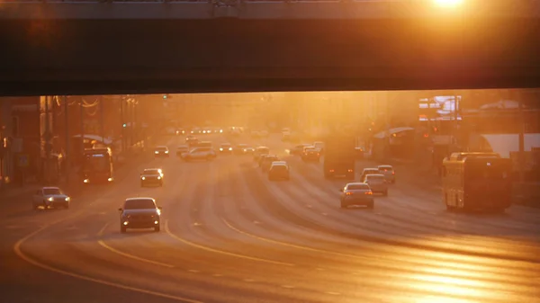 Una gran ciudad. Coches montando en la carretera bajo el puente. Puesta de sol . — Foto de Stock
