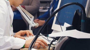 Masada oturan ve bilgisayarda çalışan beyaz gömlekli bir adam