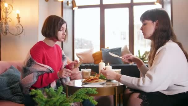 两个年轻女子坐在咖啡馆里一边吃煎饼一边说话。很棒的内饰 — 图库视频影像