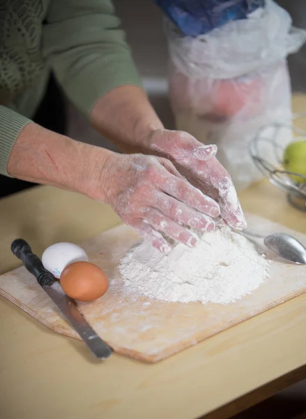 Старушка печет пирожки. Замеси тесто на столе. — стоковое фото