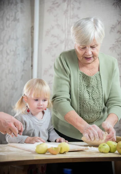 Stara kobieta co mały pies z jej wnuczka. Zagnieść ciasto — Zdjęcie stockowe