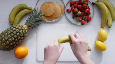 Bir kadın temizler ve muz bir kesme tahtası üzerinde keser