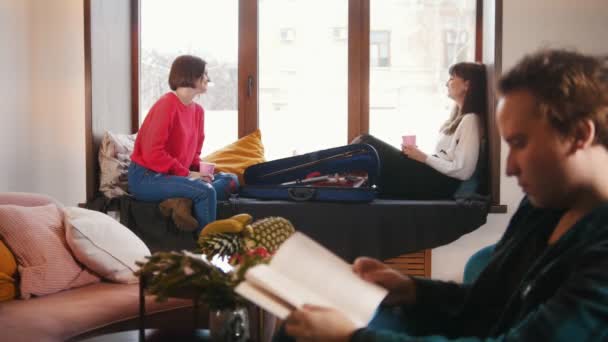 Een man is het lezen van een boek. Een vrouwelijke chatten op de achtergrond — Stockvideo