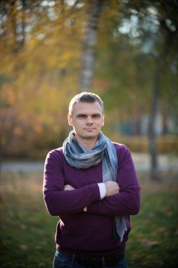 Kameranın sonbahar parkta genç biri ciddi bir bakışla bakar