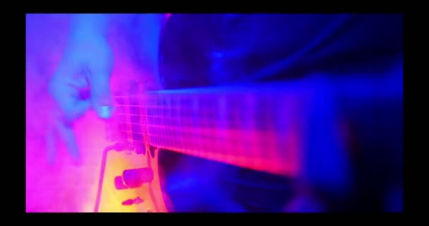Gitarristen spelar en starkt upplyst gitarr — Stockvideo