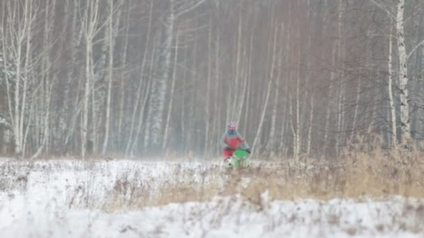 Un hombre conduciendo una moto de nieve a través del bosque — Vídeo de stock