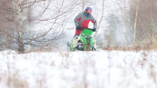 Een man een sneeuwscooter rijden in de winter forest — Stockvideo