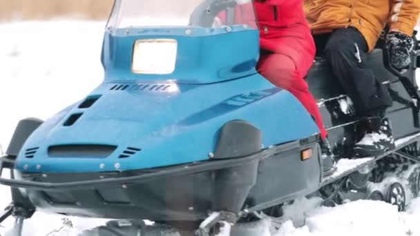 En kvinna som rider en snöskoter genom gräset i skogen vinter — Stockvideo