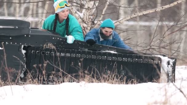 Ο τύπος με ένα κορίτσι που ρίχνεις ένα snowmobile στο δάσος — Αρχείο Βίντεο