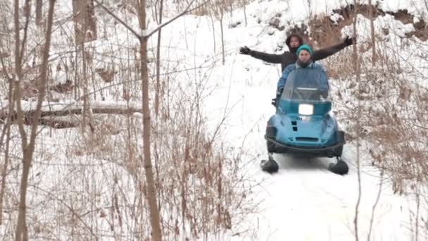 Двое мужчин спускаются на снегоходе по склону в лесу — стоковое видео