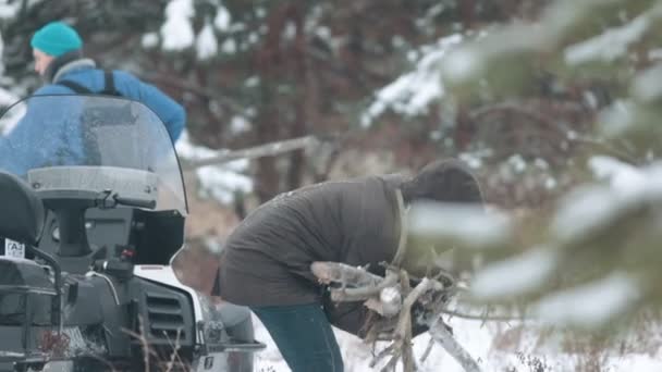 Man verzamelt takken om het licht van een brand in het bos — Stockvideo