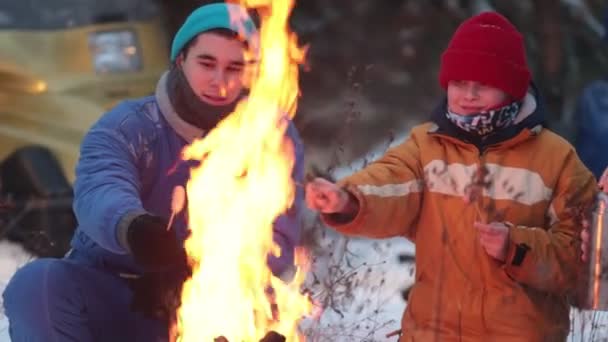 Familie bereitet Würstchen am Feuer zu und trinkt Tee im Wald — Stockvideo