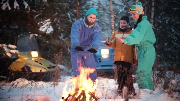 Familie soler sig ved bålet og drikker te i skoven – Stock-video