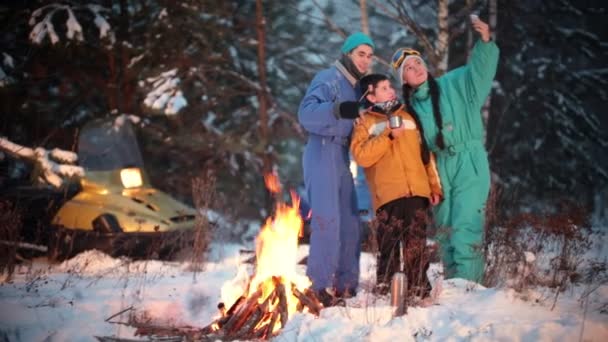 Семья делает селфи на фоне снегоходов в лесу — стоковое видео