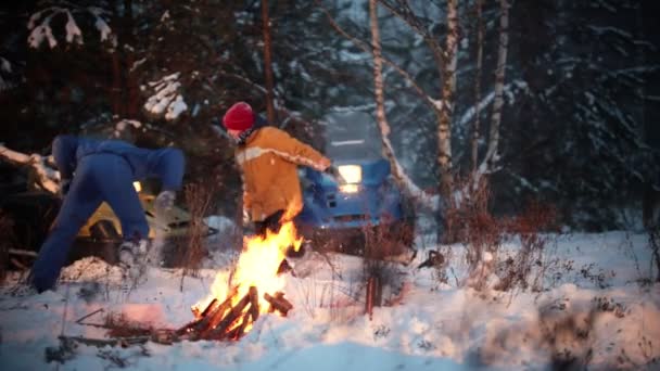 Die Familie spielt im Schneeball am Lagerfeuer im Wald — Stockvideo