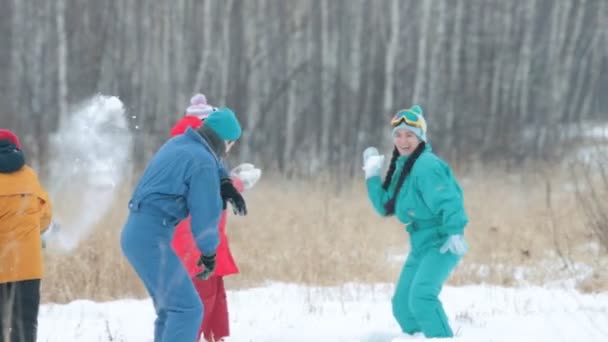 Зима. Семья в разноцветных пуховиках играет в снежки в лесу. Медленное движение — стоковое видео