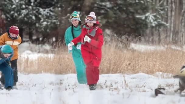 Winter. glückliche Familie in bunten Kleidern, die es genießt, mit Schnee zu spielen. Laufen und lachen. Zeitlupe — Stockvideo