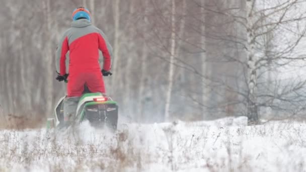 一个穿着明亮衣服驾驶雪地车的人 后面的视图 宽镜头 — 图库视频影像
