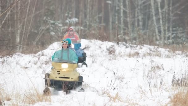 Семья в разноцветной одежде катается на снегоходах в зимнем лесу — стоковое видео