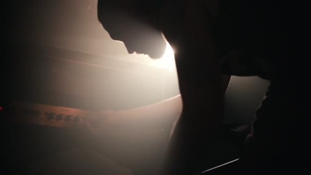 Nella luce intensa, un uomo installa l'attrezzatura per la chitarra — Video Stock