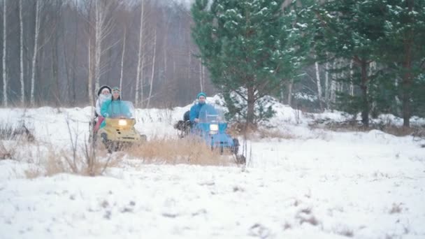 Зимовий ліс. Молоді люди катаються на снігоходах — стокове відео