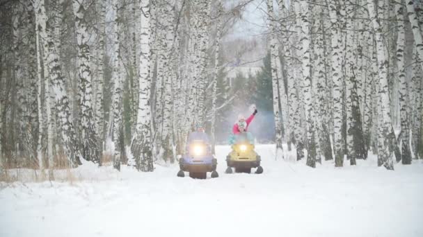 Молоді люди катаються на снігоходах у зимовому лісі. Жінка тримає димову бомбу — стокове відео