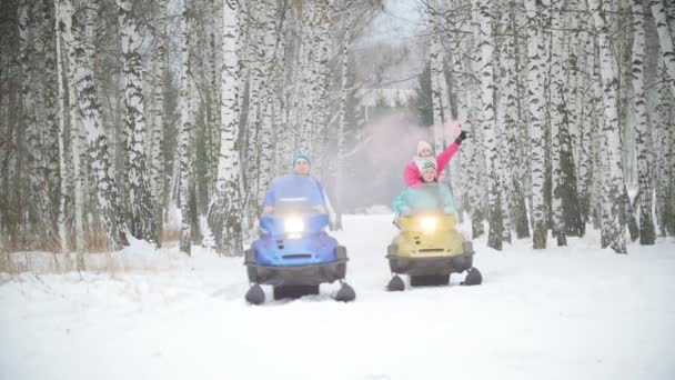 Des jeunes en motoneige dans une forêt d'hiver. Une jeune femme souriante tenant une bombe à fumée — Video