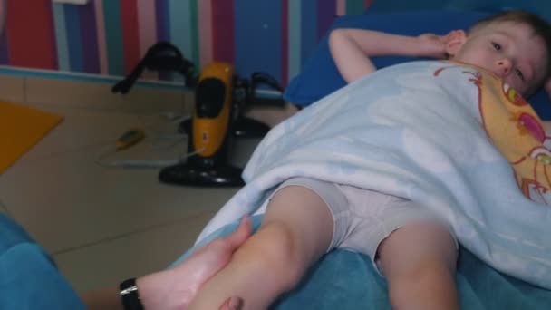 Медицинская клиника Занятие с ребенком с церебральным параличом. Массаж ног — стоковое видео
