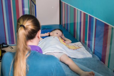Sağlık kliniği. Serebral Palsili çocuk ile bir meslek. Bebeğin önünde duran bir hemşire