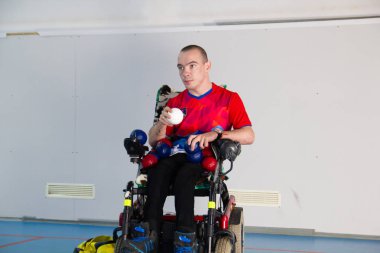 Boccia. Engelli biri tekerlekli sandalyede. Beyaz küçük bir top tutan