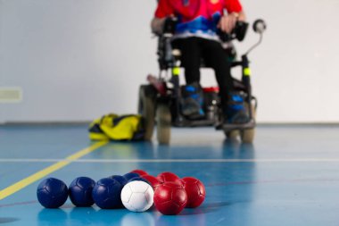 Boccia. Tekerlekli sandalyede oturan bir Engelli sporcu. Boccia oynamak için küçük topları kapatın. Üç renkli.