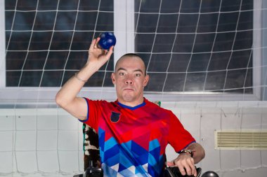 Boccia. Küçük bir mavi top sallanan bir tekerlekli sandalyede oturan bir Engelli sporcu
