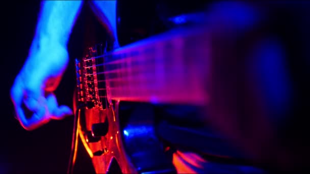 Κιθαρίστας μελωδίες και αρχίσει να παίζει στην κιθάρα του, στο φωτεινό νέον φωτισμός. — Αρχείο Βίντεο