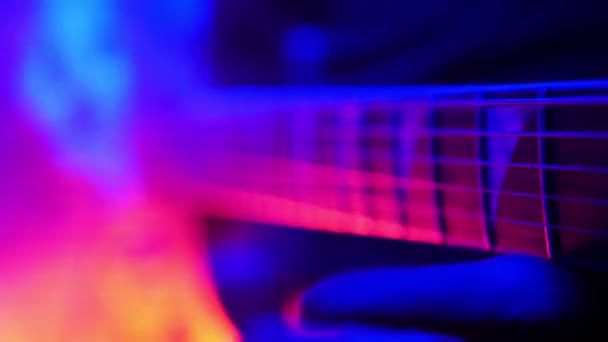 Gitarist speelt op zijn gitaar in de rook in felle neon verlichting. — Stockvideo