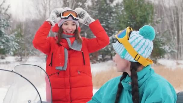 Vintern. Två unga kvinnor i färgglada jackor att sätta på glasögon och förbereda för skjutsen — Stockvideo