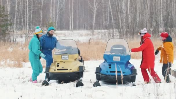 Winter. Een familie in kleurrijke jassen worden steeds op sneeuwscooters en klaar voor de rit — Stockvideo
