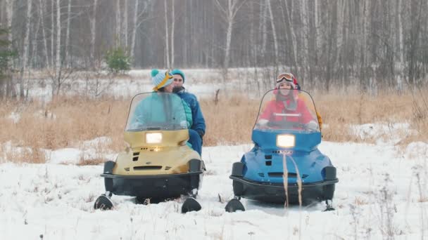 冬天。一个穿着五颜六色夹克的家庭坐在雪地摩托上, 开始骑行 — 图库视频影像